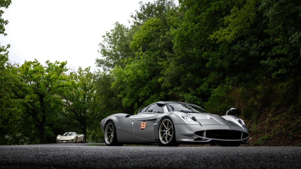 Stunning silver sports car parked on a scenic forest road, exuding elegance and speed.