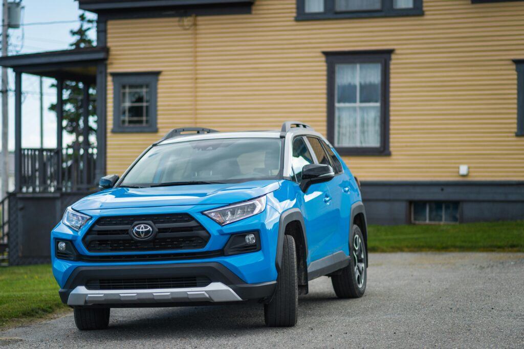 Blue Toyota RAV4 parked outside a house, showcasing modern SUV design.